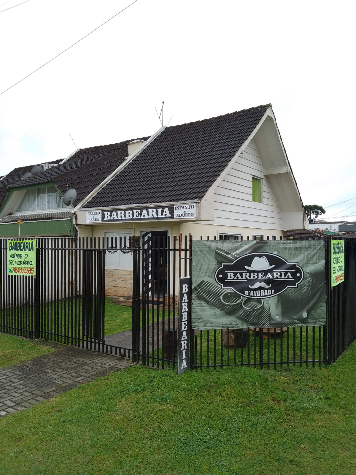 Fachada da Barbearia D'Andrade, com faixa de entrada e placa Barbearia Cabelo e Barba