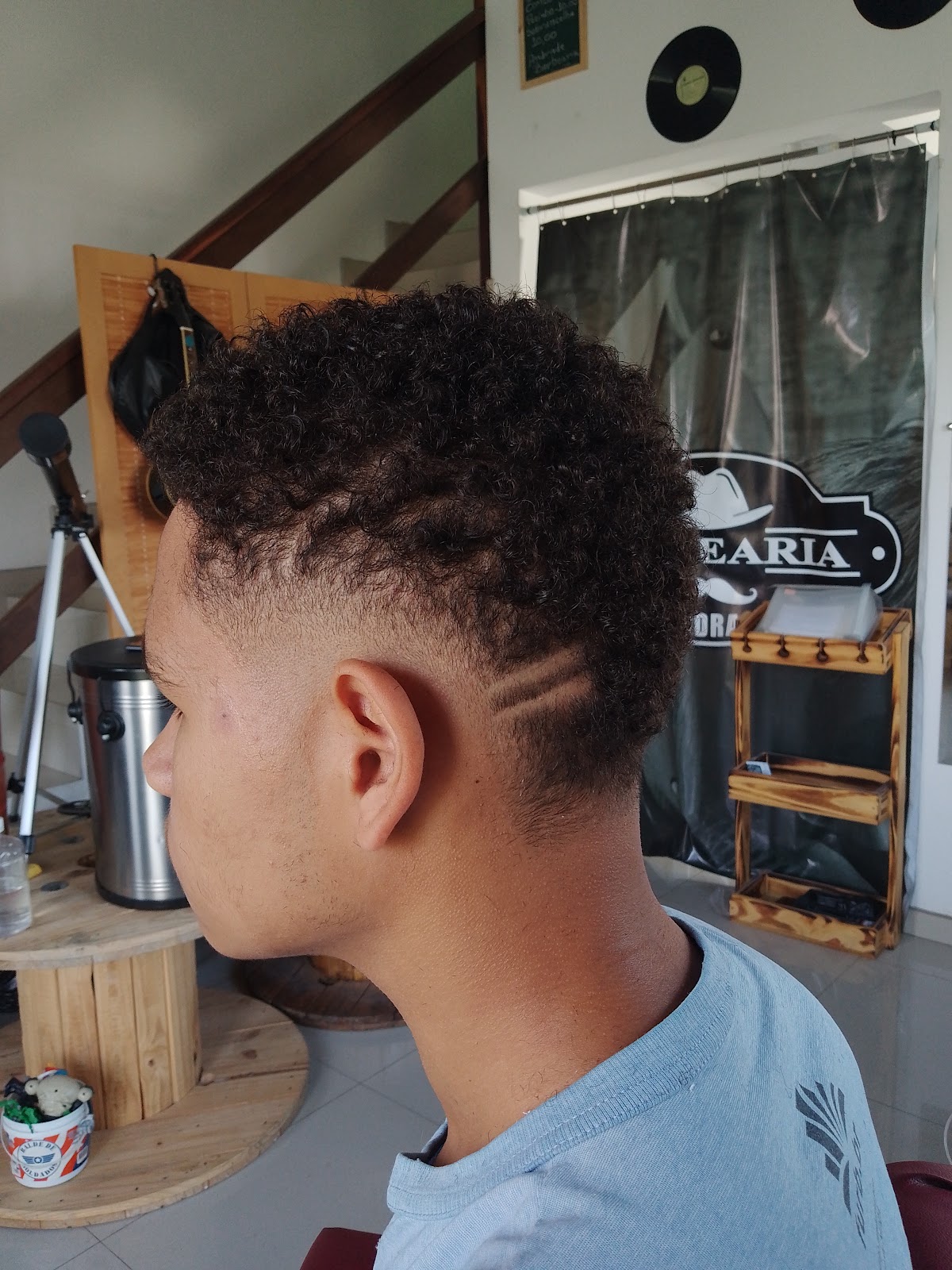Criança com corte texturizado e fade nas laterais, vista de perfil, na Barbearia D'Andrade